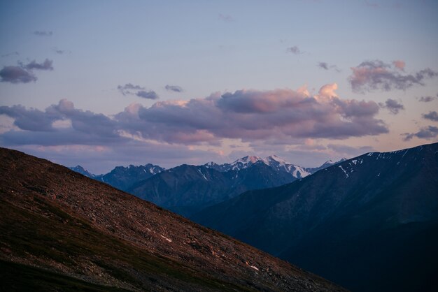 Sfeervol alpine landschap met grote bergen onder lila wolken in de hemel. Geweldig zonsopganglandschap met magenta berg. Prachtig uitzicht op de gletsjer met roze sneeuw op zonsondergang. Violet schemering hemel