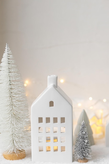 Sfeervol miniatuur wit kerstdorp Stijlvolle kleine kersthuisjes en bomen op sneeuwdeken met gloeiende lichten Kerst moderne winterdorp vakantiebanner Fijne feestdagen