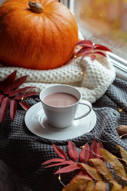 Sfeervolle compositie van de herfst met een kopje cacaopompoen en herfstbladeren