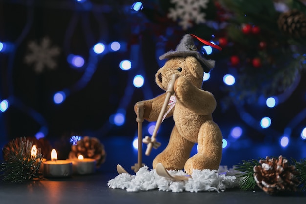 Sfeervolle kerst- of nieuwjaarssamenstelling met teddybeer, kegels, kaarsen, dennentakken en slinger.