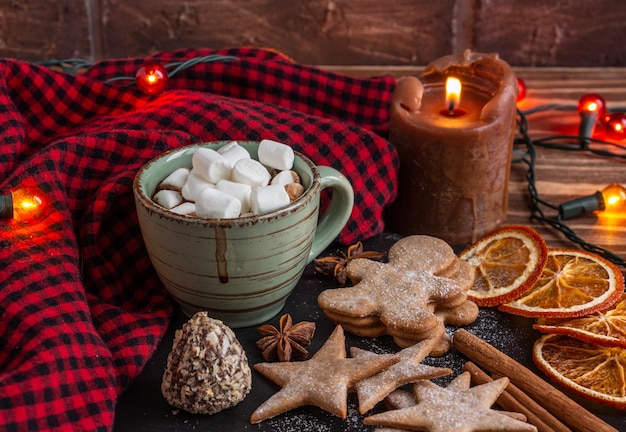 Sfeervolle kerstcompositie een kopje cacao met marshmallows kaarsen peperkoek koekjes zoet...