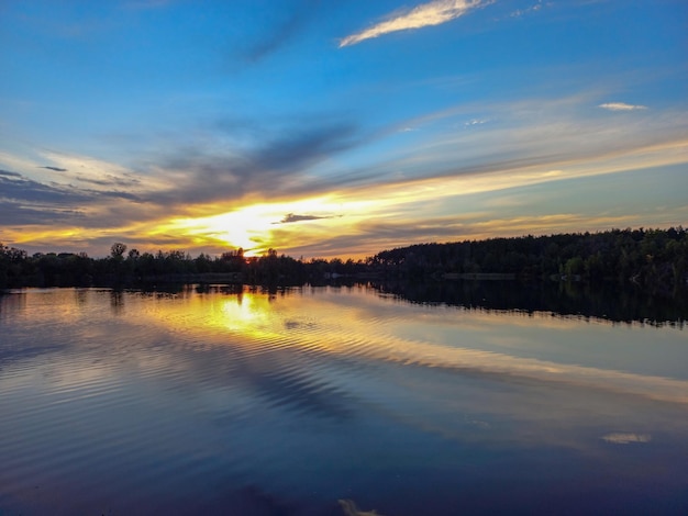 Sfeervolle zonsondergang achter bomen en reflectie in water