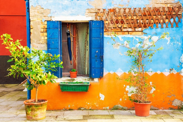 Shabby gevel van het huis en raam met blauwe luiken. Kleurrijke architectuur in Burano-eiland, Venetië, Italië.