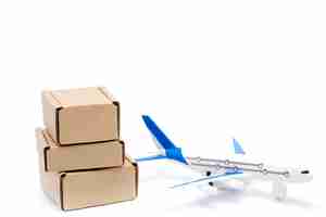 Photo shadow airplane and stack of cardboard boxes isolated on white background. concept of air cargo and parcels, airmail. fast delivery of goods and products. logistics, connection to hard-to-reach places