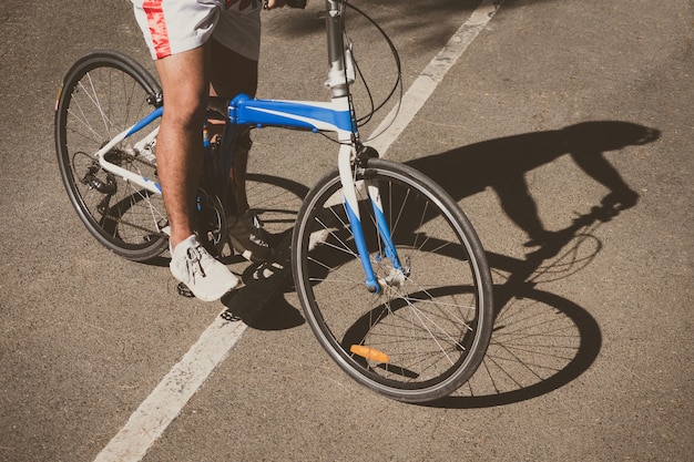 晴れた日の自転車の影とアスファルト表面上のサイクリスト。