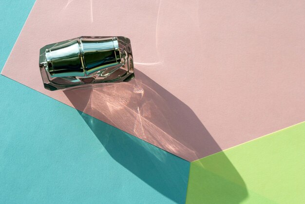 The shadow of a bottle of perfume in bright sunlight on a multi-colored background copy space