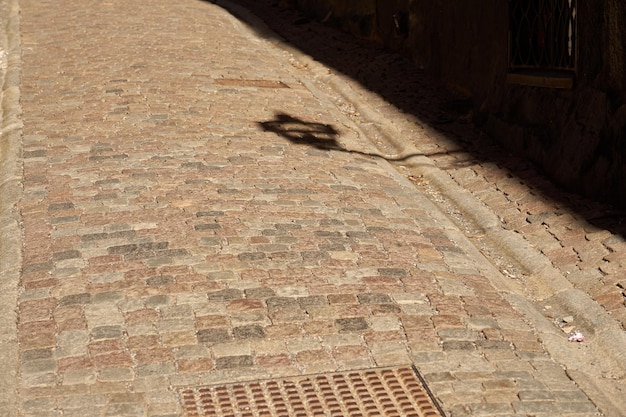 Shadow from a decorative lantern on the road made of granite tiles