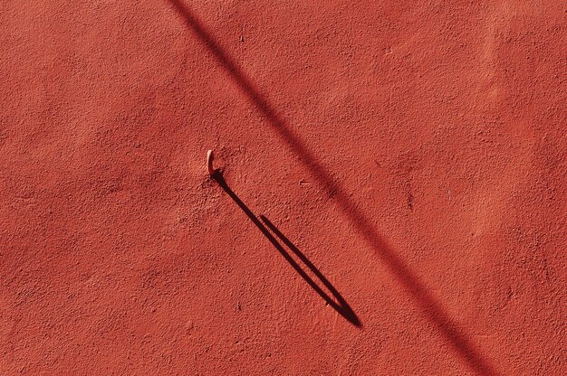 Foto ombra di un gancio di ferro sul muro rosso