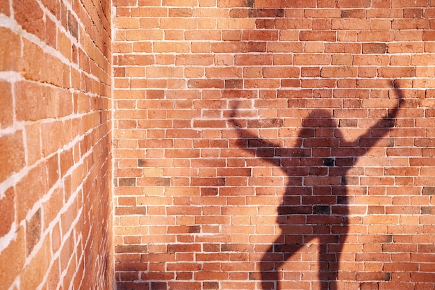 Foto ombra di un uomo su uno sfondo di muro di mattoni