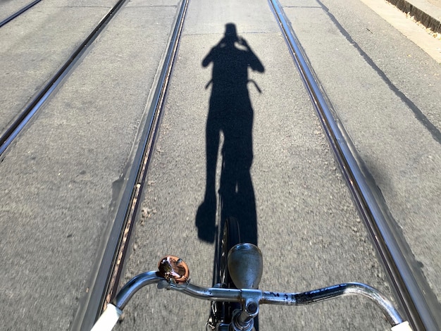 Тень человека, едущего на велосипеде по дороге.