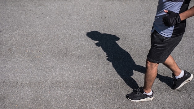 Shadow of a man running on a path in a sunny day.