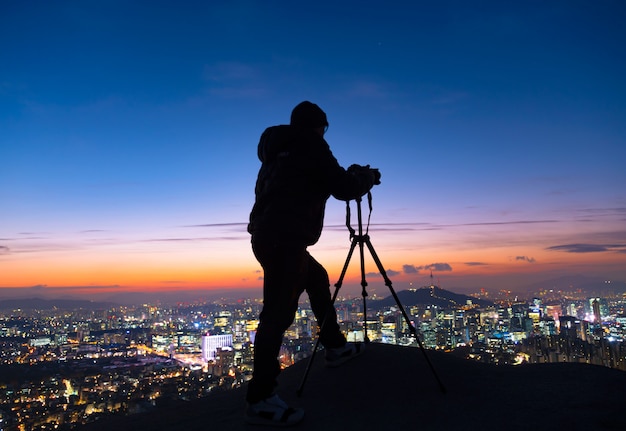 Shadow Man Standing Silhouette on background of Sunrise Sky and Photographer with a camera mounted on tripod in Seoul South Korea