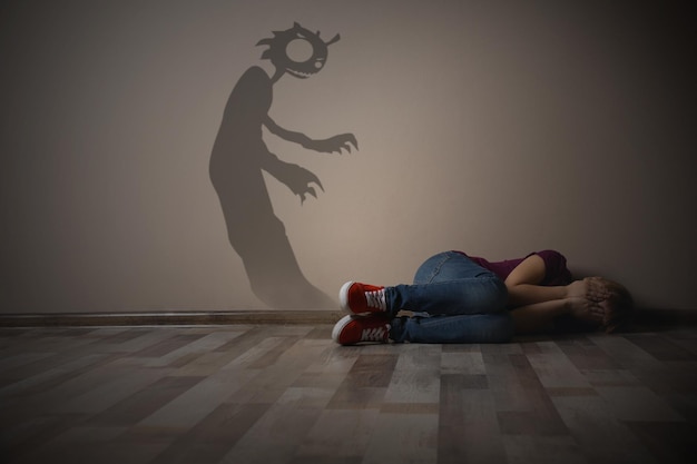 Shadow of monster on wall and scared little girl in room