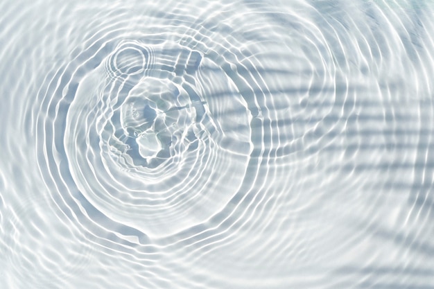 Shadow of palm leaf on transparent water and drops of water falling. Top view, flat lay.