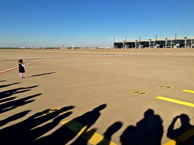 Foto ombra di persone con ragazze in piedi sulla strada dell'aeroporto