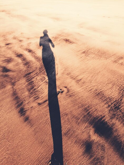 Photo shadow of person on sand and wave