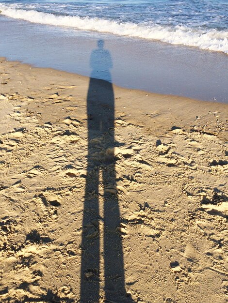 Foto ombra di una persona in piedi sulla spiaggia