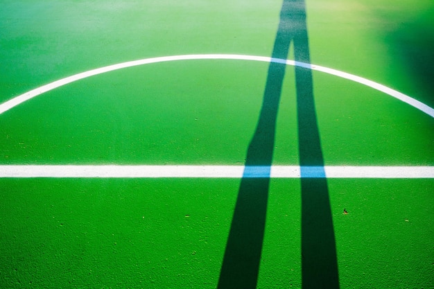 Foto ombra di una persona in piedi sul campo da basket verde