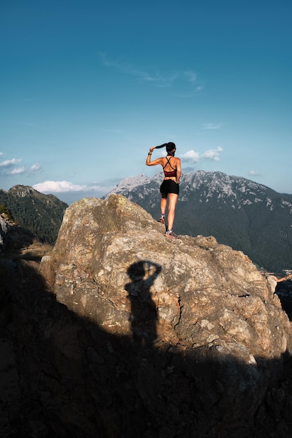 Shadow of a photographer portraying a sportswoman on a rock