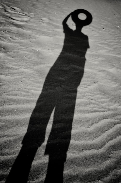 A shadow in the sand of a man with a circle instead of a head