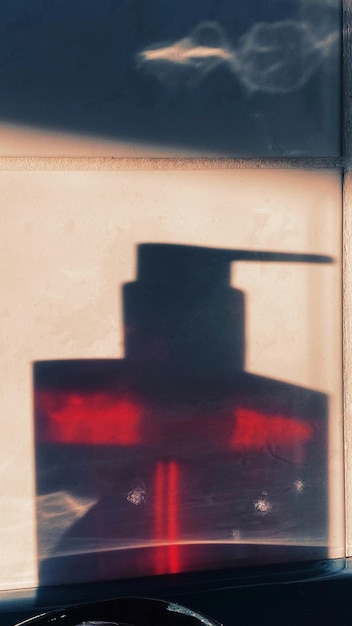 Foto ombra di un dispenser di sapone sulla parete di vetro
