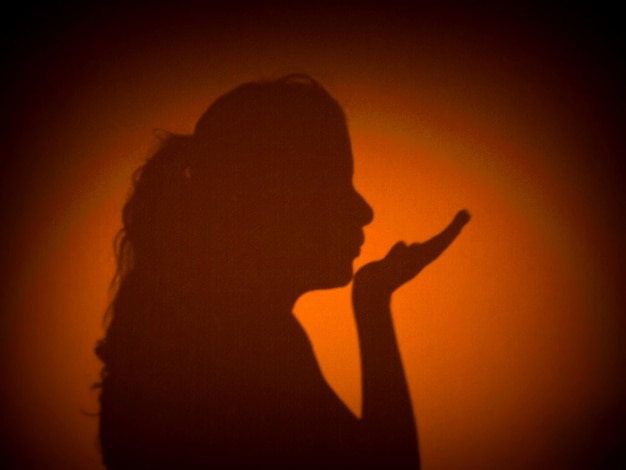 Photo shadow of woman blowing a kiss on wall