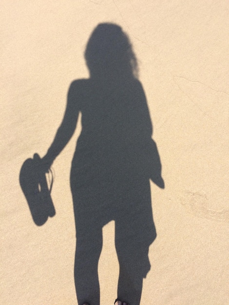 Shadow of woman on sand at beach