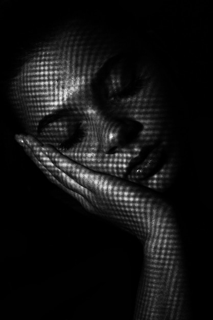Тень над женщиной, спящей на черном фоне.