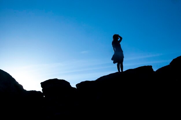 Shadow of a woman stays on rock