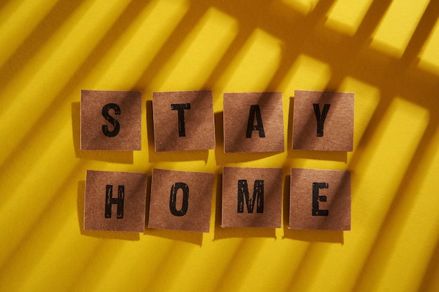 Photo shadow on the word stay home on the yellow background