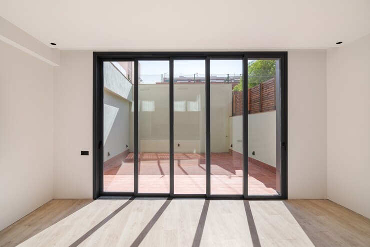 Shadows on the floor from sunlight through big windows new room with wooden floor in a refurbished a...