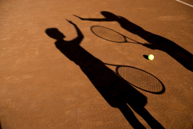 Shadows of two tennis players high fiving