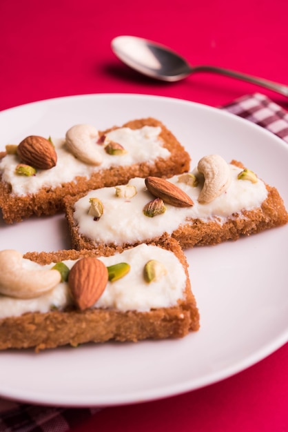 Shahi tukda of Double ka meetha is een broodpudding in ghee, gegarneerd met gecondenseerde melk, noten & Mawa/khoya. Populair Indiaas dessert, geserveerd in een bord op een humeurige achtergrond. Selectieve focus