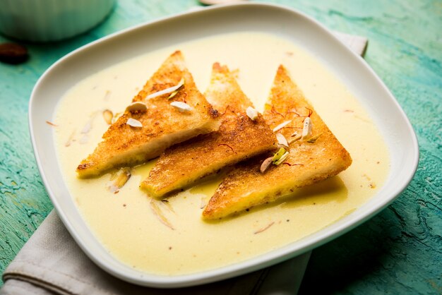 Shahi tukra or tukda or Double ka meetha is a bread pudding Indian sweet of fried bread slices soaked in rabid or sweet saffron milk garnished with dry fruits, selective focus