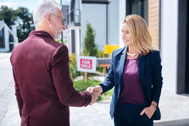 Photo shaking hand. bearded grey-haired prosperous man shaking hand of estate broker after buying big luxury house