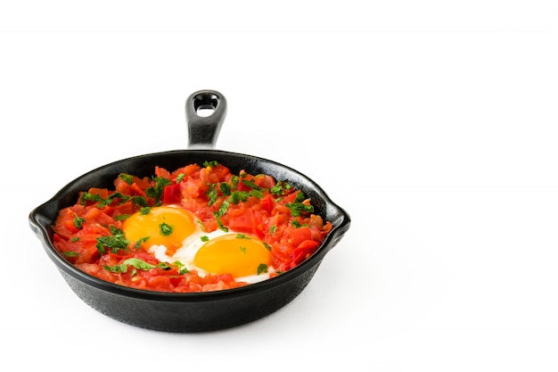 Shakshuka in iron frying pan isolated on white. Typical food in Israel.