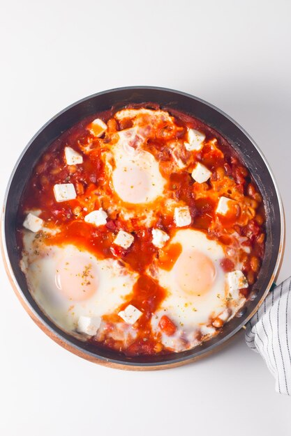 Shakshuka made of poached eggs in tomato pepper sauce