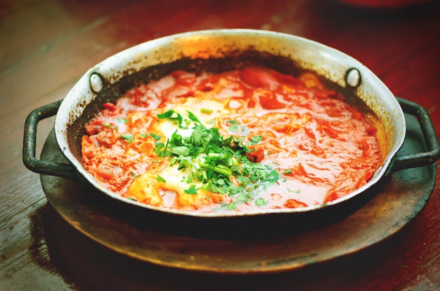 Shakshuka. Traditioneel joods eten en recept uit de Midden-Oosterse keuken. Gebakken eieren, tomaten, paprika en peterselie in een pan.