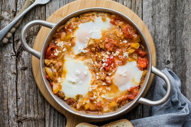 Foto shakshuka con uova, pomodoro e prezzemolo in una padella di ghisa