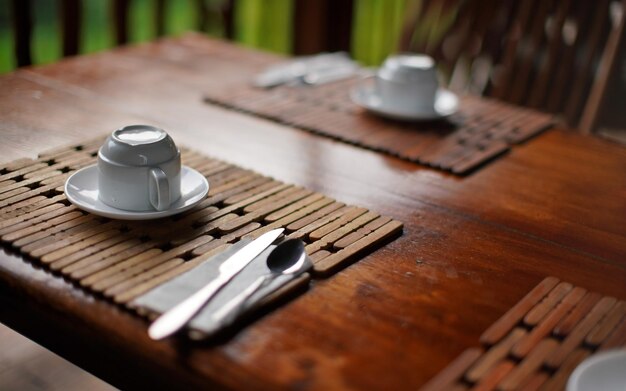 Shallow depth of field detail photo of empty coffee cup upside down on wooden table desk, morning breakfast in tropical holiday resort.