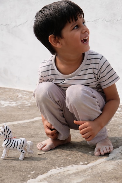 Photo shallow focus of a cheerful indian kid playing with a toy horse on a building roof