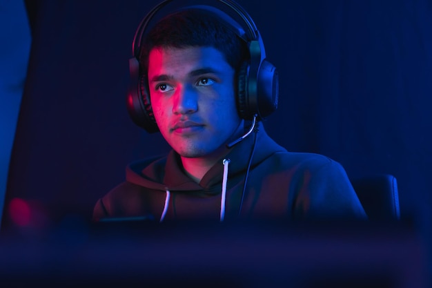Shallow focus of a Hispanic male gamer with headphones streaming an online video game