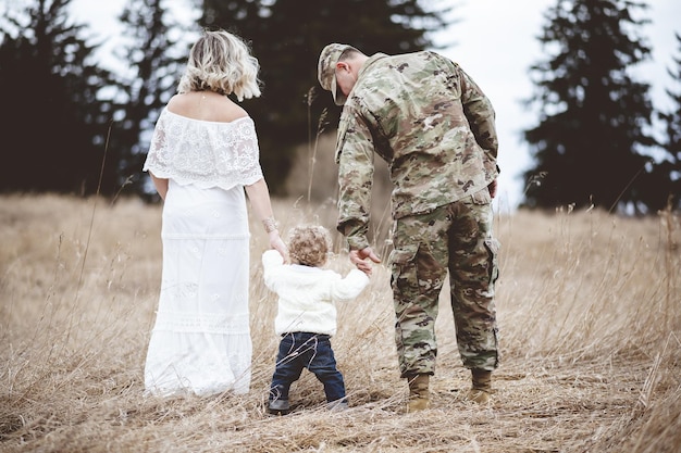 Shallow focus shot of an American soldier and his lovely wife holding their baby's hands