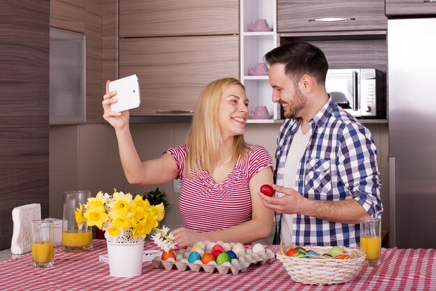 Shallow focus shot of a happy couple taking a selfie while painting Easter eggs in joy