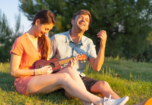 Shallow focus shot of a young couple playing ukulele in the park