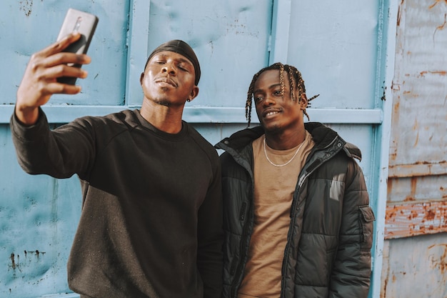 Shallow focus of two Black men taking a selfie together outside a building