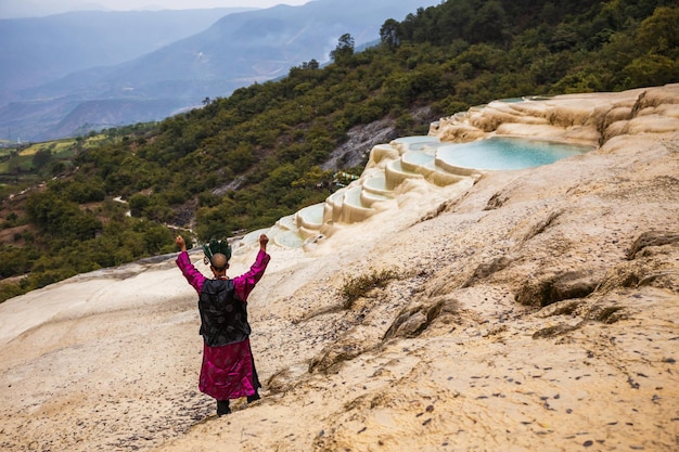 Shaman in national clothes making ritual of summoning spirits at mineral terraces in Baishutai China