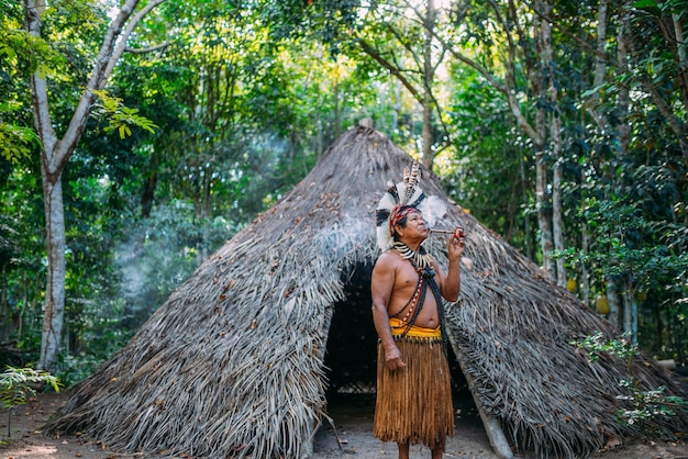 Shaman of the PataxÃ³ tribe, wearing feather headdress and smoking a pipe