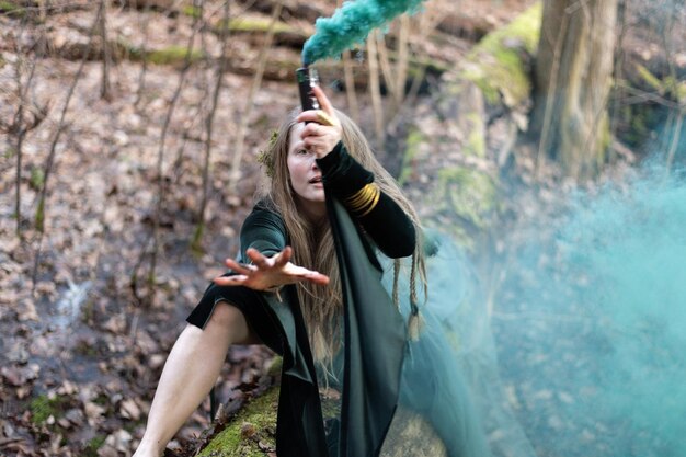 Shaman vrouw met hand groene rookbom op boomstam in sping dag
