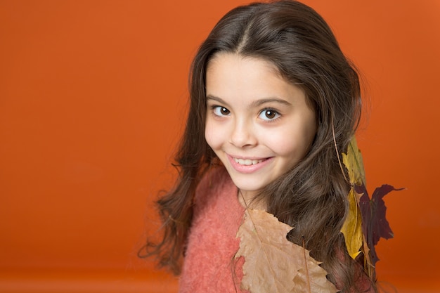 Shampoo die naar herfst ruikt. Gelukkig meisje draagt kleurrijke bladeren in lang haar. Shampoo met herfstgeuren. Shampoo voor normaal, droog of vet haar. Haarverzorgingsroutine. Herfst warmte haar shampoo, kopieer ruimte.